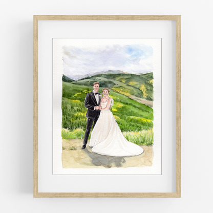 Framed watercolor portrait of a bride and groom embracing in a green mountain landscape.