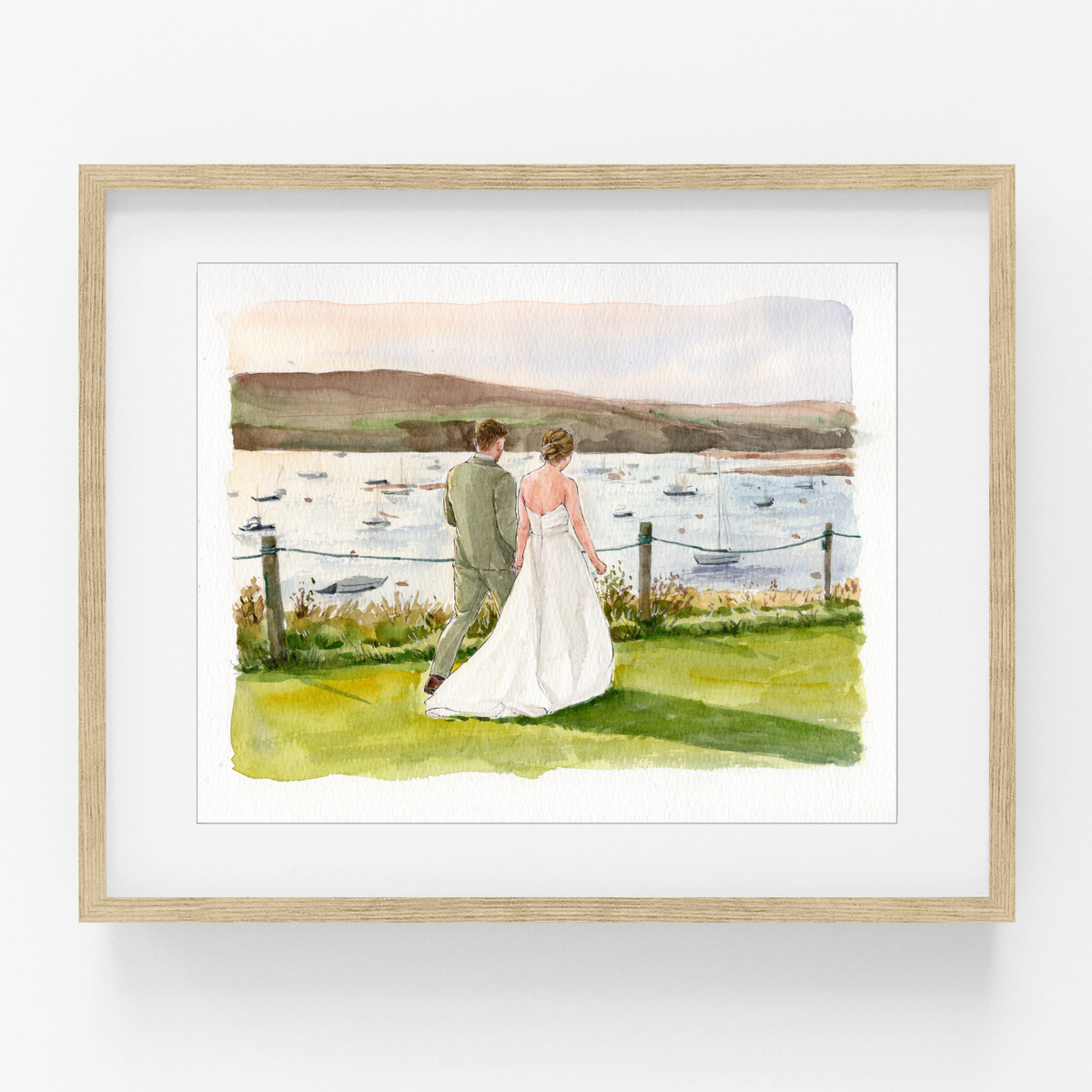 Framed watercolor wedding portrait of a bride and groom beside a lake with hills in the background.