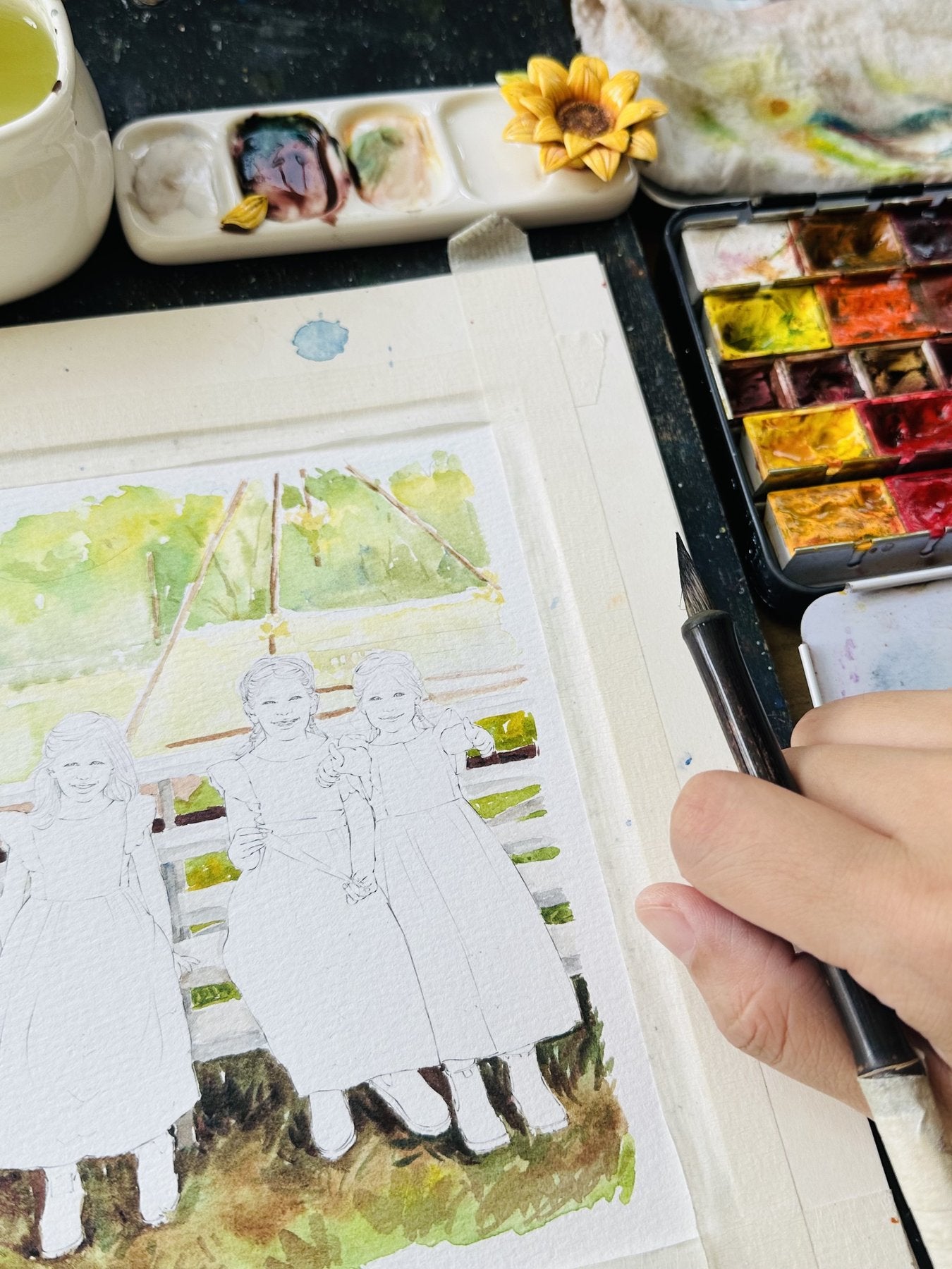 A watercolor portrait of three sisters being painted by hand