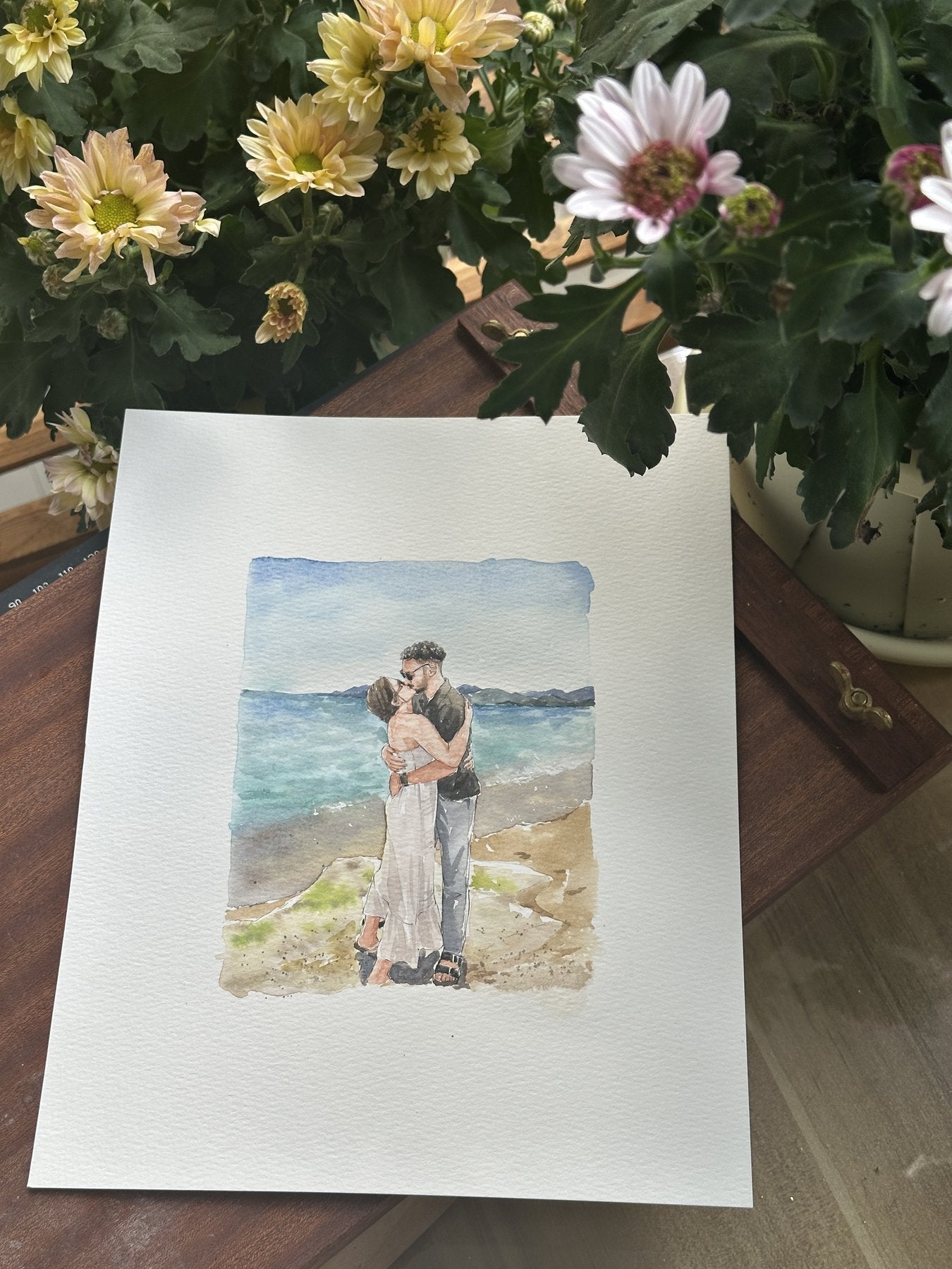 Finished watercolor portrait of a couple embracing by the ocean