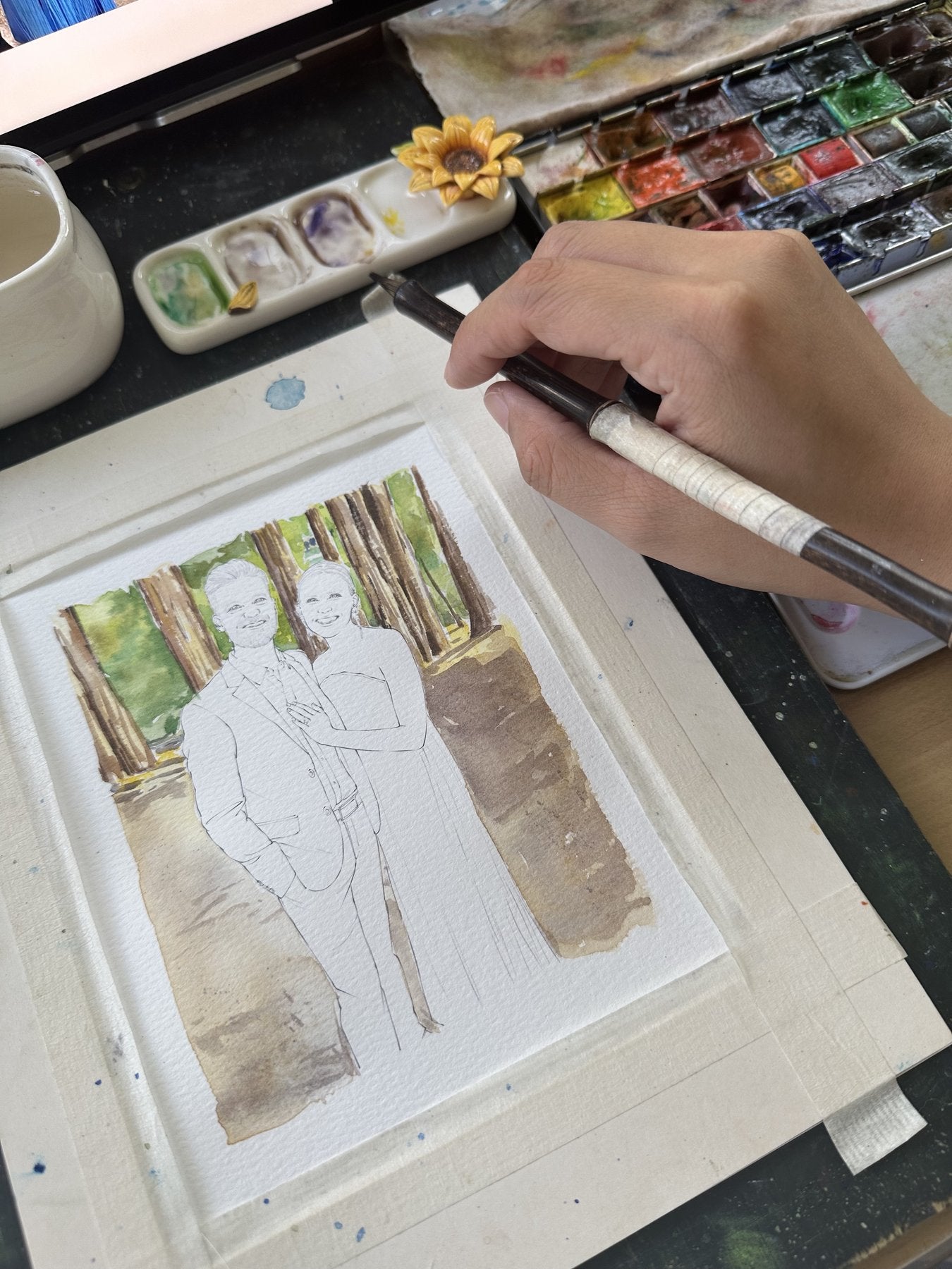 A watercolor portrait of a couple being painted among redwood trees