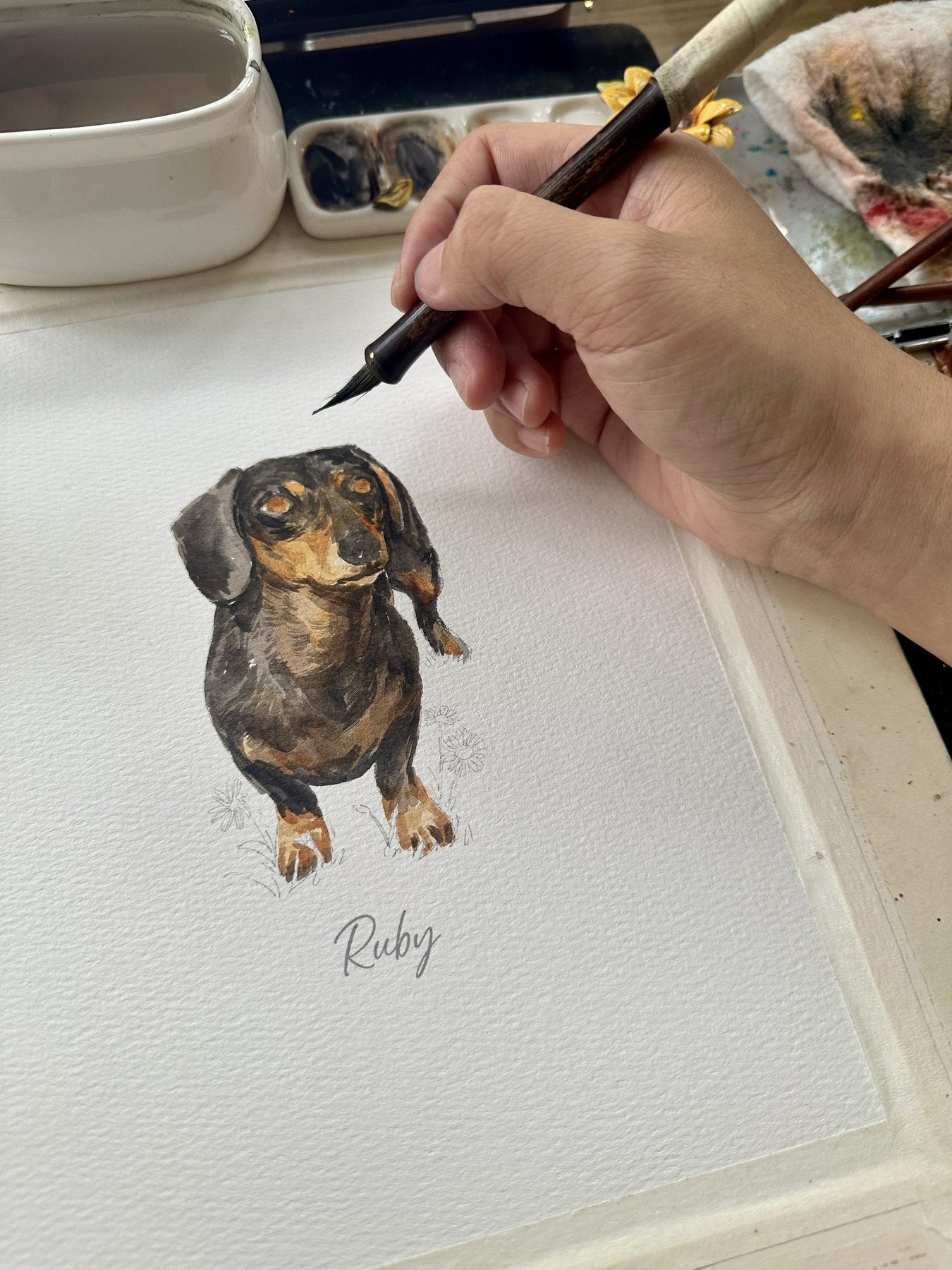 Artist layering watercolor details on Ruby's pet portrait